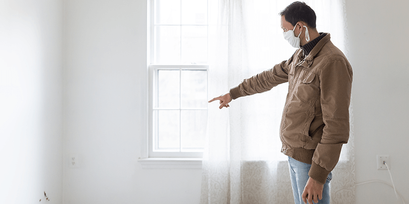 man in house points to broken wall