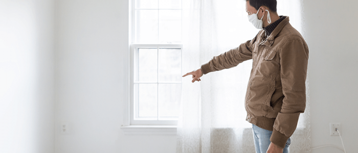 man in house points to broken wall